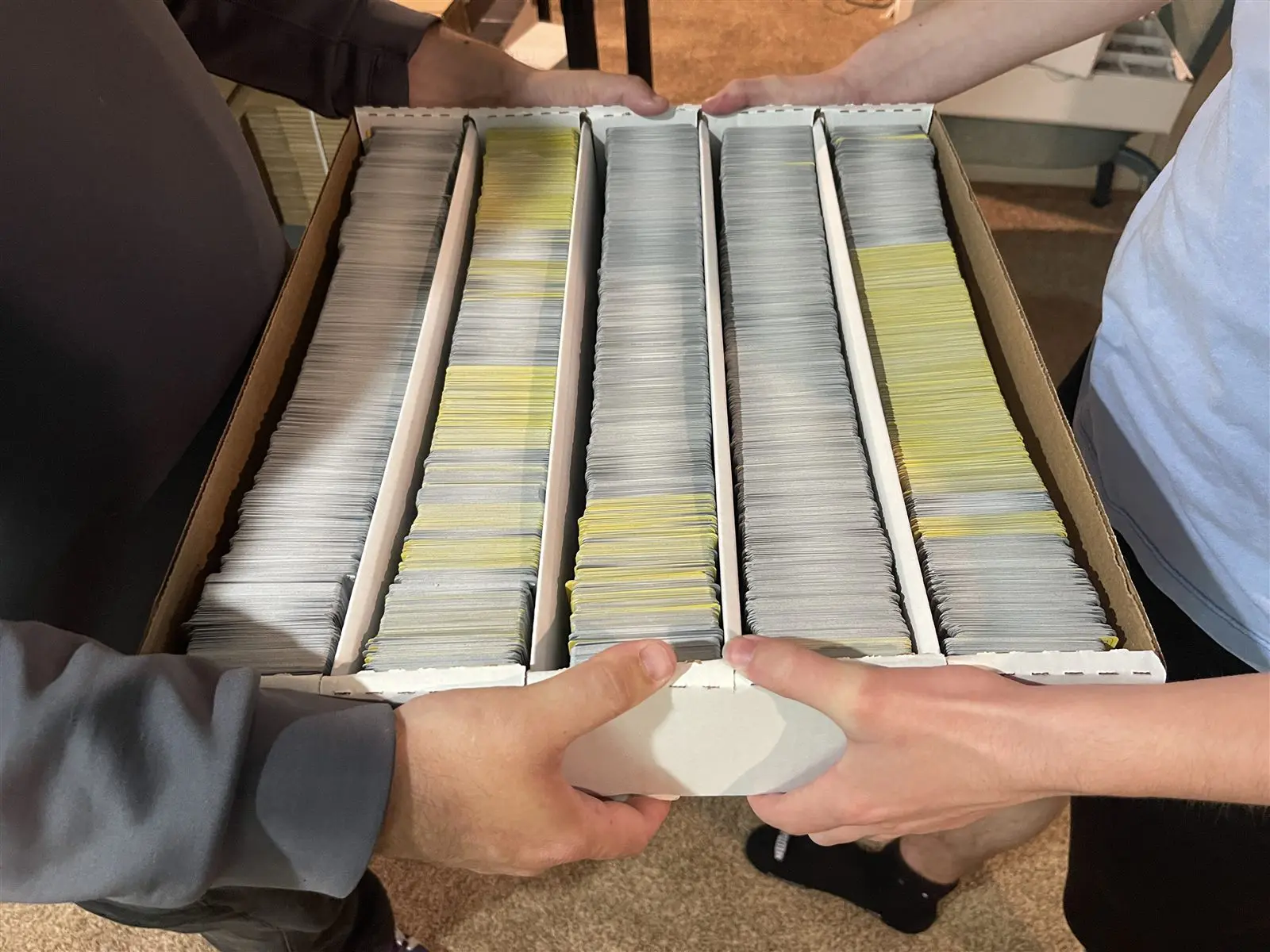 Two people passing a long box of Pokemon cards between them