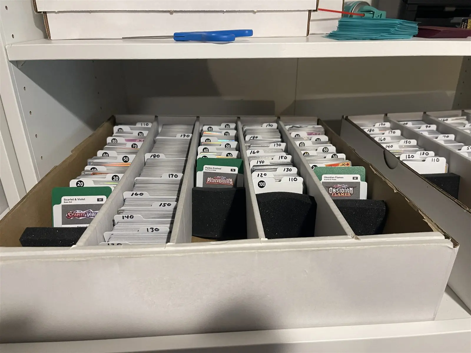 A drawer of Pokemon cards sorted by set, with set dividers